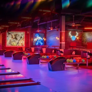 A modern-looking bowling alley lit up with purple lights for evening bowling.