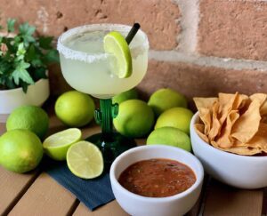 A classic margarita in a cactus-style marg glass with chips and salsa.