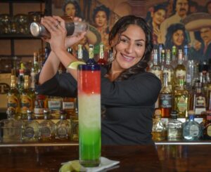 A female bartender is shaking a margarita.