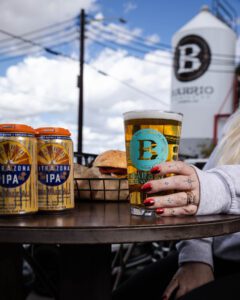 A woman's hand holding a pint of Barrio beer.