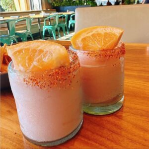 Two paloma margaritas garnished with pink salt and grapefruit wedges.